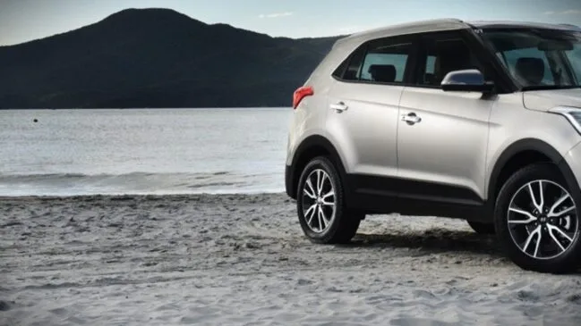 Carro estacionado na areia da praia com maresia no litoral de Santa Catarina